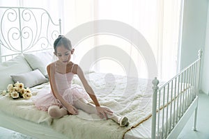 Little girl 9 year dancing ballet with white bed in bedroom at home, Ballerina young girl practicing ballet