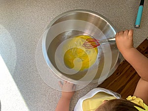 Little Girl Adding Mixing Eggs While Baking with Parents