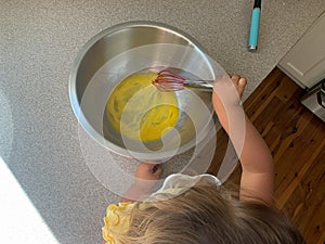 Little Girl Adding Mixing Eggs While Baking with Parents