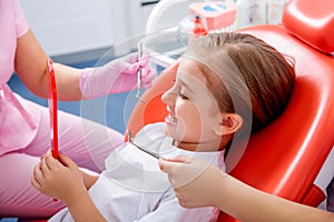 Little girl is afraid to show her teeth to a pediatric dentist. child girl in white clothes at reception at a pediatric dentist