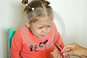 Little girl afraiding of trimming fingernails by manicure scissors