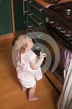 Little girl at   age of 10 months playing in   kitchen with   stove