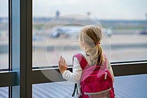 Little Girl at the Airport Waiting for Boarding at the Big Window. Cute Kid Stands at the Window against the Backdrop of