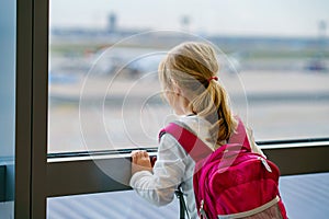 Little Girl at the Airport Waiting for Boarding at the Big Window. Cute Kid Stands at the Window against the Backdrop of