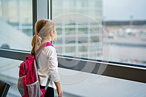 Little Girl at the Airport Waiting for Boarding at the Big Window. Cute Kid Stands at the Window against the Backdrop of