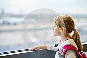 Little Girl at the Airport Waiting for Boarding at the Big Window. Cute Kid Stands at the Window against the Backdrop of