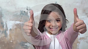 Little girl alone isolated on painted wall smiling showing thumbs up
