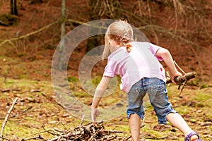 Little girl alone searching wood and food in the forest