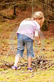 Little girl alone searching wood and food in the forest