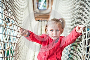 Little girl in amusement park rope tunnel