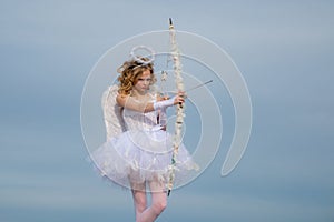 Little girl with angel wings and halo. Toddler girl wearing angel costume white dress and feather wings. Sweet angel