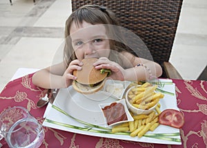 A little girl with an appetite eats a burger photo