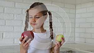 Little girl with apples in the kitchen. Child bites eating an apple