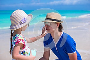 Little girl apply sunscreen on nose of her dad