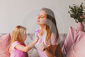 Little girl applying parfume on her mother