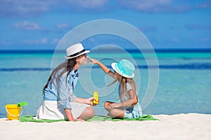 Little girl applying sun cream to her mother nose