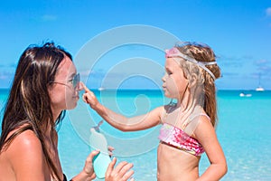 Little girl applying sunblock cream on her mom