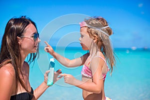 Little girl applying sunblock cream on her mom