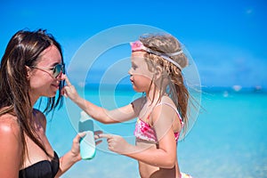 Little girl applying sunblock cream on her mom