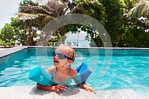 Little girl with armbands learn to swim in swimming pool