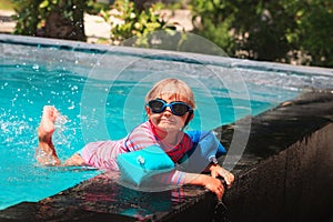 Little girl with armbands learn to swim in swimming pool