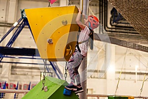 Little girl ascending in rock climbing gym