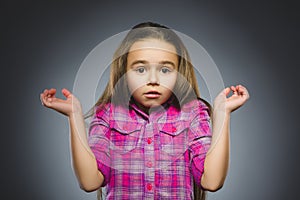 Little girl with astonished expression while standing against grey background