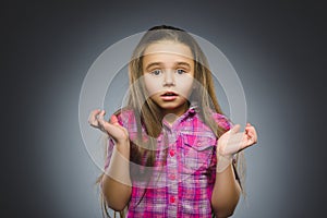 Little girl with astonished expression while standing against grey background