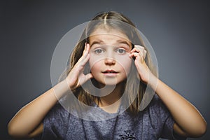 Little girl with astonished expression while standing against grey background