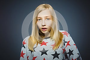 Little girl with astonished expression while standing against grey background