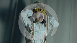 Little girl with an autumn leaf mask closing the ears with her hands and screaming. Handheld shooting.