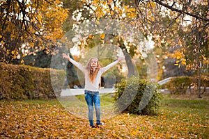 Little girl in autumn orange leaves. happy little child, baby girl laughing and playing in the autumn on the nature walk outdoors.