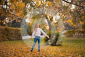 Little girl in autumn orange leaves. happy little child, baby girl laughing and playing in the autumn on the nature walk outdoors.