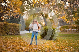 Little girl in autumn orange leaves. happy little child, baby girl laughing and playing in the autumn on the nature walk outdoors.