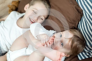 Little girl and baby boy, brother and sister playing in parents bed. Family with children in the morning. Kids play in white