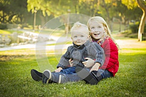 Little Girl with Baby Brother Wearing Coats at the Park