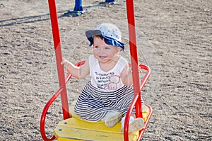 Little girl baby in a cap plays with toys in a sandbox with sand on the playground