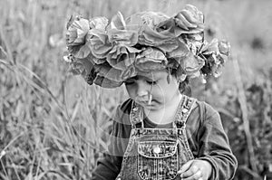 Little girl baby playing happy on the poppy field with a wreath, a bouquet of color A red poppies and white daisies, wearing a den