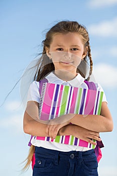 Little girl with a backpack and colored notepad on