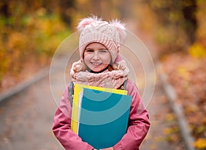 Little girl with backpack holding folders