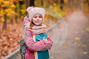 Little girl with backpack holding folders