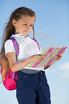 Little girl with a backpack looking on the notepad