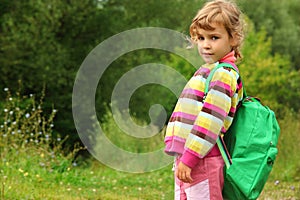 Little girl with backpack outdoor in summer