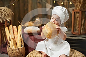 Little girl baker eating fresh round bread