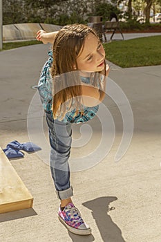 A little girl balances herself on one leg as she just finished tossing a bean bag