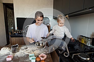 a little girl and a bald sphinx cat watch attentively as a caring mother cooks food in the kitchen