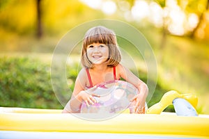 Little girl with ball in the garden swimming pool.