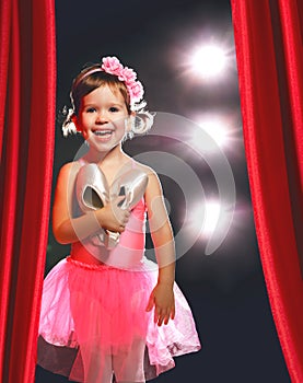 Little girl ballerina ballet dancer on stage in red side scenes