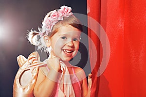 Little girl ballerina ballet dancer on stage in red side scenes