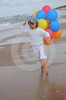 Little girl with balloons on the beach